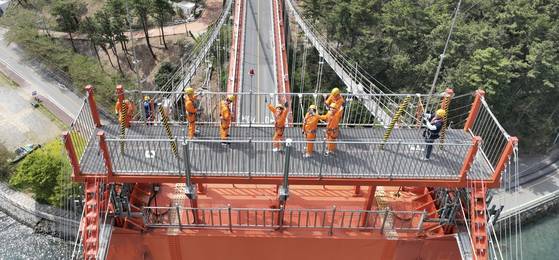 지난 19일 한국 최초 현수교인 경남 남해대교의 주탑 꼭대기 전망대에서 '브리지 클라이밍' 행사 참가자들이 사진 촬영 중인 드론을 향해 손을 흔들고 있다. 사진 남해군