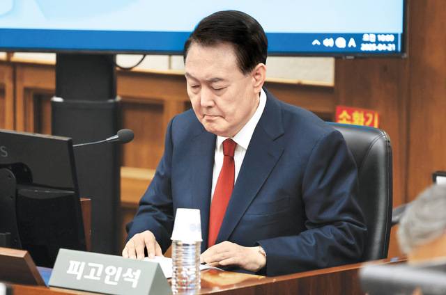 윤석열 전 대통령이 21일 서울 서초구 서울중앙지법 417호 대법정에서 진행된 내란 우두머리 혐의 재판에서 피고인석에 앉아 서류를 들여다보고 있다. 재판부의 촬영 허가가 내려지면서 윤 전 대통령이 피고인석에 앉은 모습이 이날 처음 공개됐다. 최현규 기자