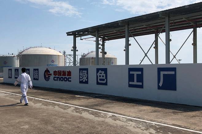 중국 하이난성 난산 액화천연가스(LNG) 터미널에서 한 노동자가 중국해양석유총공사(CNOOC) 로고 앞을 지나가고 있다. (사진=로이터)