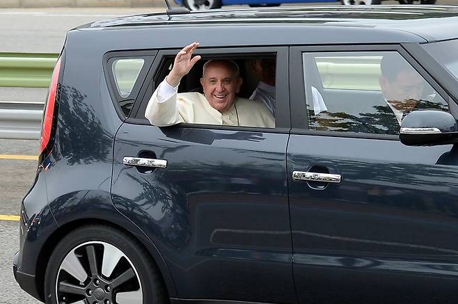 한국을 방문한 프란치스코 교황이 14일 오전 경기 성남시 수정구 서울공항을 나서며 기아 쏘울에 탑승해 환영객들에게 손흔들고 있다. 프란치스코 교황은 취임 초기부터 방탄차를 이용하지 않겠다고 공언했으며, 실제 한국 방문 때도 가장 작은 차를 타고 싶다는 뜻을 한국 천주교 교황방한준비위원회에 전달해온 것으로 알려졌다. 이에 따라 방한 기간 중 교황은 기아자동차의 1600cc급 소형 승용차인 쏘울을 탔다. 2014.8.14/뉴스1