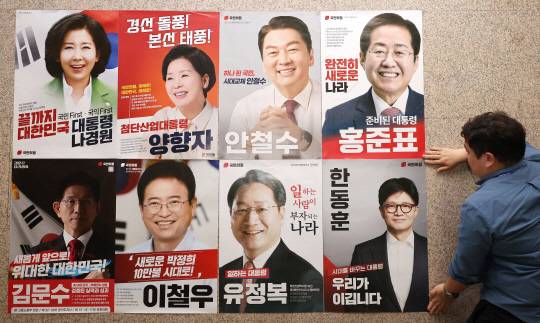 국민의힘 관계자가 지난 20일 국회 본청 당 사무실 앞에서 대선 경선 후보자 포스터를 붙이고 있다. [연합뉴스]