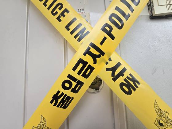 지난 21일 오후 모녀가 숨진 채 발견된 경기 수원 권선구 아파트 현관에 경찰 출입금지 폴리스라인이 쳐져 있다. 현관 밖엔 모녀가 사용하던 것으로 추정되는 바퀴달린 장바구니와 금융결제원에서 발송한 우체국 등기, 파손된 현관 문고리 등이 놓여있었다. 손성배 기자