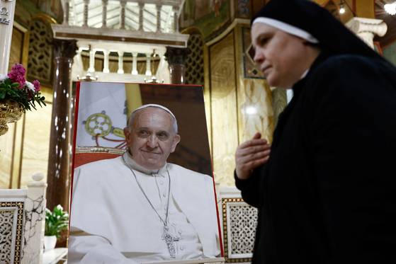 21일(현지시간) 이탈리아 로마 산타마리아 아돌로리아 성당에서 한 수녀가 프란치스코 교황의 사진 앞을 지나가고 있다. 로이터=연합뉴스