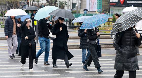 Pedestrians walk by Gwanghwamun Square in central Seoul with umbrellas on April 14. [NEWS1]