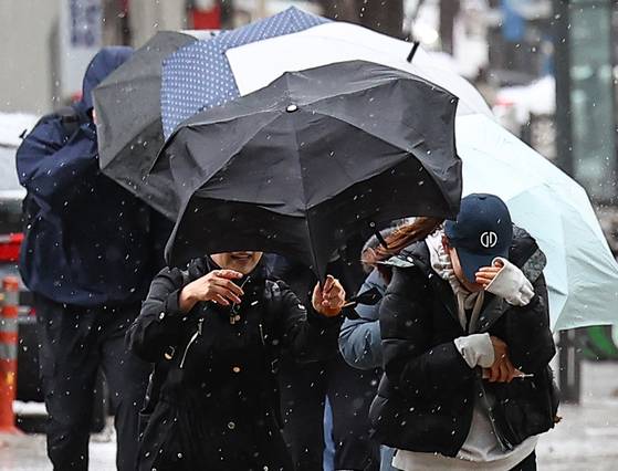 Pedestrians shield themselves from rain and heavy winds on a street in Seocho District, southern Seoul on April 13. [YONHAP]