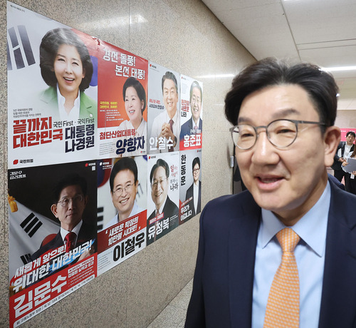 대선 경선 후보자들 포스터 앞 지나는 권성동 원내대표 [사진 = 연합뉴스]