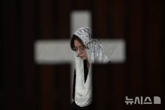 [브라질리아=AP/뉴시스] 21일(현지 시간) 브라질 브라질리아 대성당에서 열린 프란치스코 교황 추모 미사 중 한 신도가 기도하는 모습이 고해소 문틈 사이로 보이고 있다. 2025.04.22.