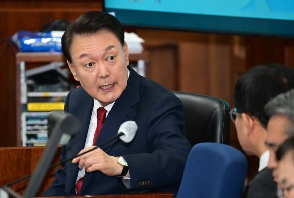 변호인단과 얘기 나누는 尹 - 12·3 비상계엄을 선포해 내란 우두머리 혐의로 재판에 넘겨진 윤석열 전 대통령이 21일 서울 서초구 서울중앙지법 417호 법정에서 열린 2차 공판에서 변호인단과 대화를 하고 있다. 사진공동취재단