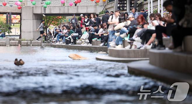 낮 최고기온이 25도를 기록하는 등 초여름 날씨를 보인 23일 오후 서울 중구 청계천을 찾은 시민들이 독서를 하고 있다. 2025.4.23/뉴스1 ⓒ News1 김성진 기자
