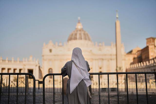 한 수녀가 22일 바티칸 광장을 구분하기 위해 이탈리아 로마에 설치된 펜스 앞에서 성 베드로 대성전을 바라보며 서 있다. 로마=AP 연합뉴스