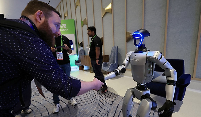&nbsp;CES 2025 개막인 지난 1월 7일 오전(현지시간) 젠슨 황 엔비디아 최고경영자(CEO) 글로벌 기자간담회가 열린 미국 네바다주 라스베이거스 퐁텐블루 호텔 엔비디아 전시관에서 휴머노이드 로봇 유니트리 G1이 관람객과 악수하고 있다. 연합뉴스