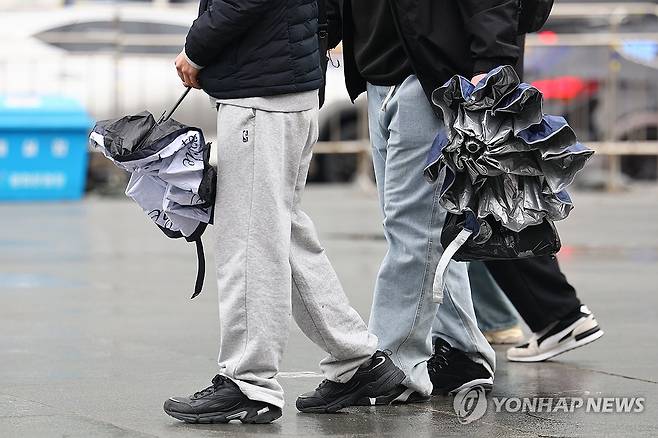 '우산 쓰긴 애매해' (서울=연합뉴스) 서대연 기자 = 약한 비가 내리며 흐린 날씨를 보인 16일 서울 종로구 광화문 광장에서 시민들이 우산을 접어 손에 들고 이동하고 있다. 2025.3.16 dwise@yna.co.kr