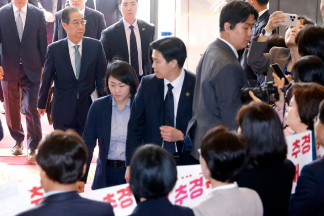 한덕수 대통령 권한대행이 24일 추가경정예산안 시정연설을 위해 국회에 도착해 본회의장으로 향하는 사이 더불어민주당 의원들이 팻말 시위를 하고 있다. 연합뉴스