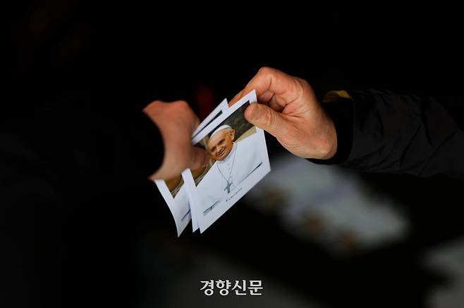 23일 서울 명동대성당에 마련된 프란치스코 교황 빈소를 찾아 조문을 마친 한 신도가 교황의 사진이 담긴 엽서를 건네받고 있다. 2025.4.23 이준헌 기자