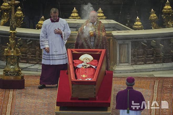 [바티칸시국=AP/뉴시스] 23일(현지 시간) 바티칸의 성 베드로 대성당에서 궁무처장 케빈 조셉 패럴 추기경이 프란치스코 교황의 시신 주위에 향을 뿌리고 있다. 프란치스코 교황의 시신은 사흘간 대성당에 안치돼 일반 신자들의 조문을 받는다. 2025.04.23.