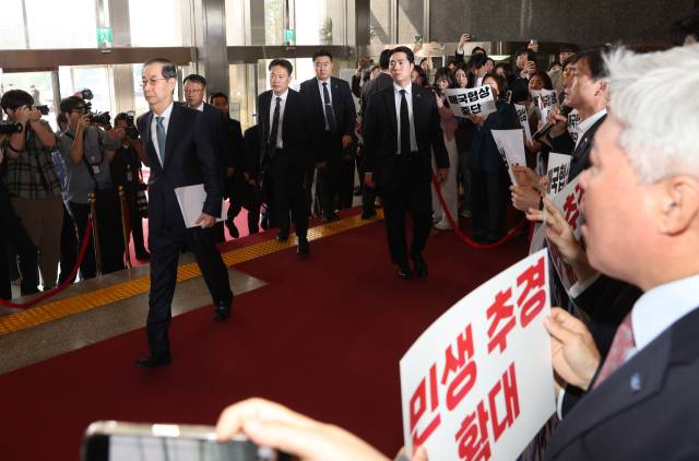 ▲한덕수 대통령 권한대행 국무총리가 24일 추가경정예산안 시정연설을 위해 서울 여의도 국회에 도착해 본회의장으로 향하는 사이 더불어민주당 의원들이 팻말 시위를 하고 있다. ⓒ연합뉴스