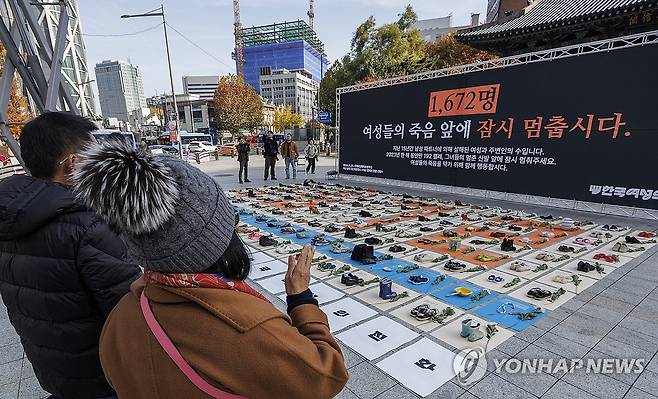 한국의 여성 살해의 실태를 신발 192켤레로 상징 작년 11월 25일 세계 여성 폭력 추방 주간을 맞이해 한국여성의전화가 서울 종로구 보신각 앞에서 개최한 여성 살해를 규탄 퍼포먼스를 관광객들이 지켜보고 있다. [연합뉴스 자료사진]