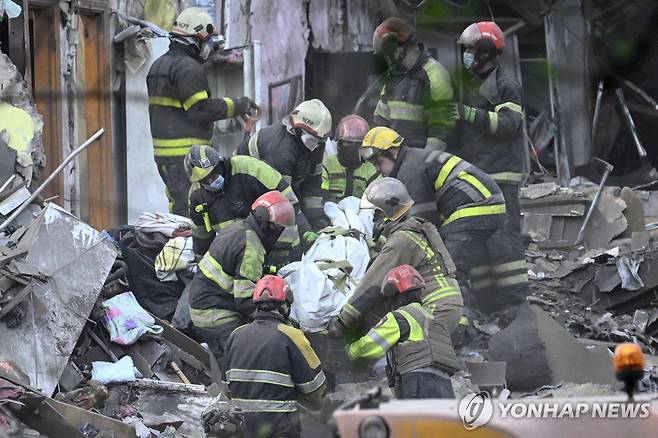 24일(현지시간) 우크라이나 키이우에서 구조대원들이 러시아의 미사일 공습으로 인한 사망자 시신을 수습하고 있다.  [AFP 연합뉴스]