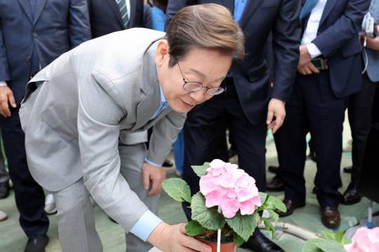 더불어민주당 이재명 대선 경선 후보가 25일 전남 나주시 전남농업기술원 에너지자립형 온실을 방문해 꽃을 살펴보고 있다. 연합뉴스