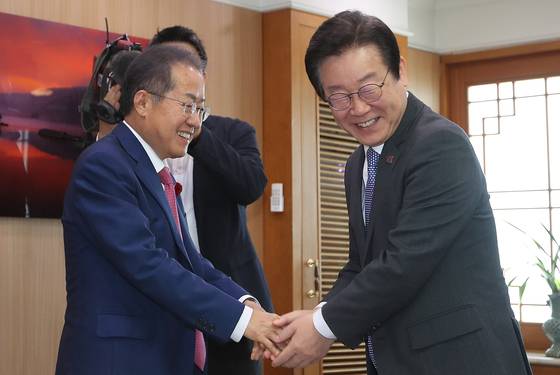 Hong Joon-pyo, left, shakes his hand with liberal presidential candidate Lee Jae-myung in Daegu City Hall on May 10, 2023. [NEWS1]