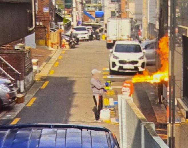 봉천동 아파트 방화 유력 용의자가 21일 서울 관악구 봉천동 한 빌라 앞에서 아파트에 불을 내기 전 농약살포기 추정 도구를 이용해 불을 지르고 있다.  [연합]
