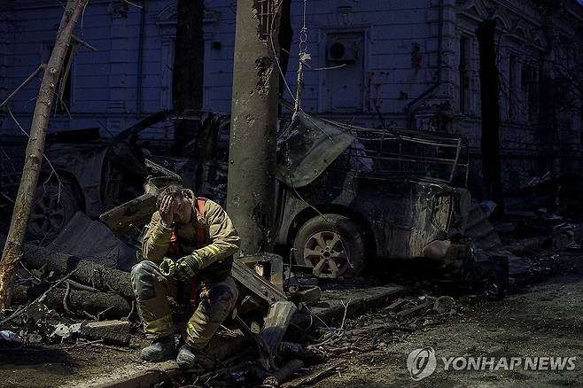 러시아 미사일에 파괴된 우크라이나 수미주 대학 근처에서 쭈그려 앉은 현지 구조대원 [AP 연합뉴스 자료사진. 재판매 및 DB 금지]