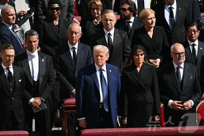 도널드 트럼프 미국 대통령과 부인 멜라니아 여사가 26일 (현지시간) 바티칸의 성 베드로 광장에서 열린 프란치스코 교황의 장례 미사에 참석해 기립을 하고 있다. 2025.04,27 ⓒ AFP=뉴스1 ⓒ