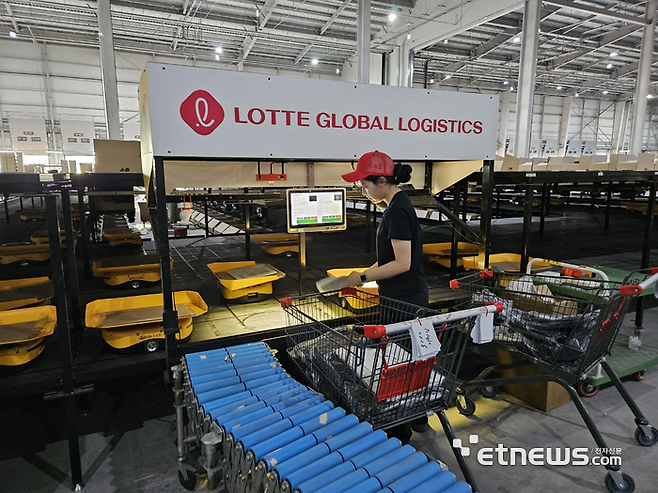 작업자가 진천 풀필먼트센터 B2B 소터에서 상품을 로봇에 담고 있다. 〈사진=민경하 기자〉