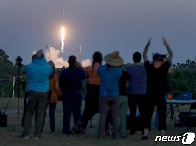 27일 (현지시간) 플로리다주 케이프 커네버럴 우주군 기지의 40번 발사대에서 고도 230마일의 궤도에 배치될 스타링크 V2 미니 위성을 탑재한 민간 우주업체 스페이스 X의 팰컨 9 로켓이 발사되는 모습을 보며 사람들이 환호하고 있다. ⓒ AFP=뉴스1 ⓒ News1