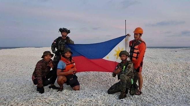 중국의 행위에 대응해 필리핀 측 또한 남중국해의 어느 모래언덕에서 자국 국기를 들고 있는 사진을 공개했다