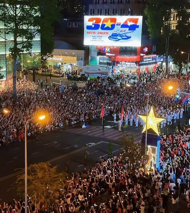 베트남 통일절 50주년 행사를 보기 위해 몰린 사람들. 도심 건물들에는 베트남 국기인 금성홍기가 내걸렸다. /온라인캡처