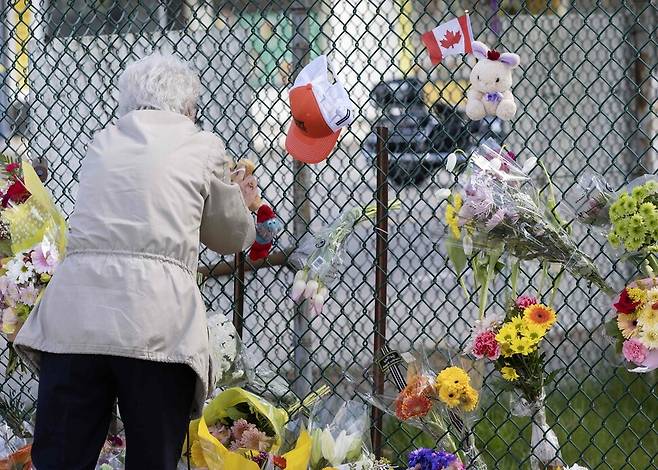 캐나다 밴쿠버 차량 돌진 사망 사고가 발생한 다음날인 27일, 사고 장소 근처에 꾸려진 추모 공간에 한 시민이 찾아와 추모 물품을 놓고 기리고 있다. AFP연합뉴스