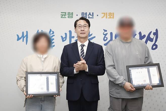 정명근 화성시장이 28일 시청에서 전화금융사기(보이스피싱) 조직의 수거책을 붙잡는 데 기여한 택시기사 부부에게 용감한 시민 표창장을 수여하고 있다. 화성시 제공