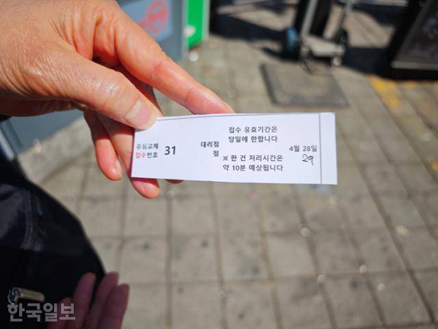 28일 오전 서울 동작구 한 SK텔레콤 대리점 앞에서 한 가입자가 다음 날(29일) 유심교체가 가능하다고 쓰인 대기표를 들고 있다. 김진욱 기자