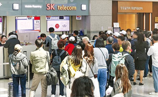< 공항서도 ‘대기 인파’ > 28일 오전 인천국제공항 제1여객터미널 내 SK텔레콤 로밍센터 앞에 유심을 교체하려는 사람들이 차례를 기다리고 있다. 이날 유심 교체 서비스가 개시된 오전 10시 전부터 로밍센터에 사람이 몰리며 혼선을 빚었다.   임형택 기자