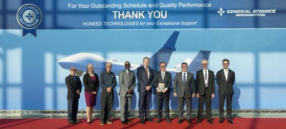 Representatives from General Atomics and Huneed Technologies, including General Atomics Aeronautical Systems Vice President Charles McVicker, fifth from left, and Huneed Chairman Eugene Kim, third from right, pose for a commemorative photo. [HUNEED TECHNOLOGIES]