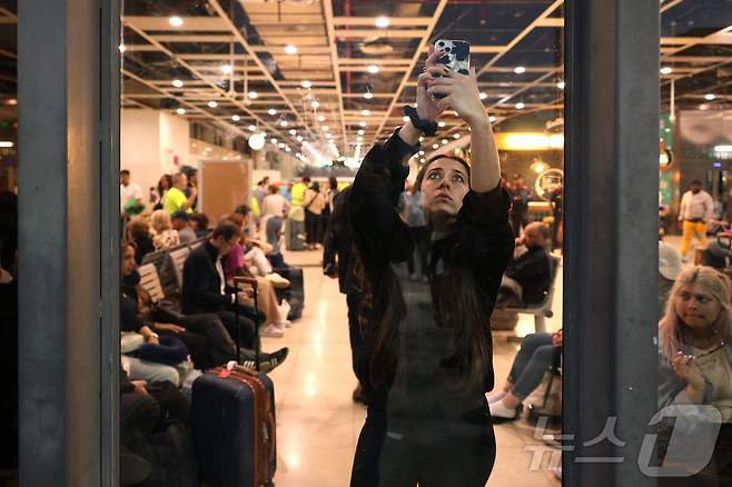 이베리아 반도에 대규모 정전이 발생한 28일(현지시간) 스페인 바르셀로나 산츠 기차역에서 한 시민이 스마트폰 네트워크를 잡기 위해 전화기를 들고 서 있다. ⓒ AFP=뉴스1