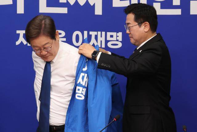 박찬대 더불어민주당 대표 직무대행 겸 원내대표가 28일 서울 여의도 국회에서 열린 최고위원회의에서 이재명 더불어민주당 제21대 대통령 선거 후보에게 선거운동복을 입혀주고 있다. 뉴시스