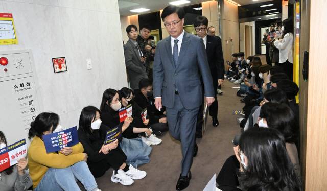 ▲ 28일 강원대학교 춘천캠퍼스 대학본부 교무회의실에서 대학평의원회가 열려 강원대와 강릉원주대 통폐합 신청서 수정안이 가결됐다. 정재연 강원대 총장이 통폐합에 반대하는 대학 구성원들 사이로 지나가고 있다. 김정호 기자