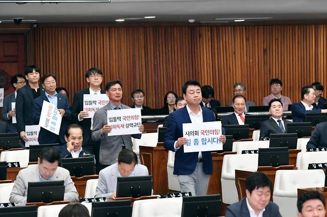 서울시의회 민주당 의원들이 25일 항의 문구가 담긴 피켓을 들고 의회에 입장하고 있다. 서울시의회&nbsp;