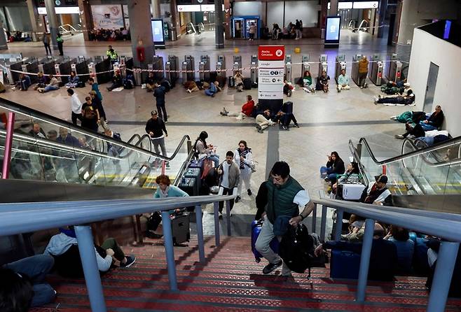 대규모 정전 사태로 인해 이베리아반도 전역과 프랑스 남부가 영향을 받은 가운데, 여행객들이 스페인 마드리드 아토차역 바닥에 앉거나 누워 밤을 보낼 준비를 하고 있다. 2025. 4. 28[사진 = AFP 연합뉴스]
