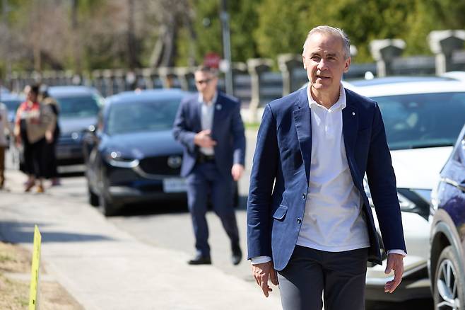 마크 카니(오른쪽) 캐나다 총리가 28일(현지시간) 온타리오주 오타와에서 열리는 총선에 투표하기 위해 투표장으로 이동하고 있다. [EPA]