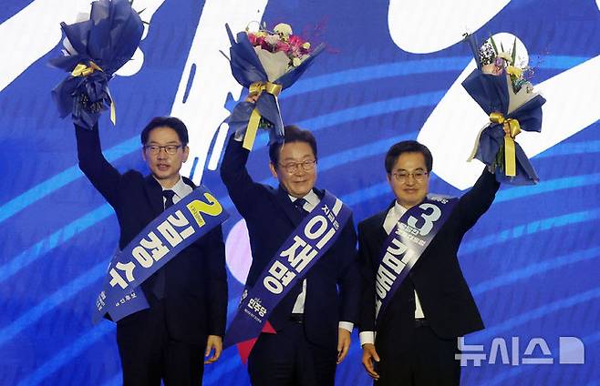 [고양=뉴시스] 조성우 기자 = 더불어민주당 제21대 대통령 선거 후보에 선출된 이재명(가운데) 후보가 27일 경기도 고양시 킨텍스에서 열린 제21대 대통령 선거 후보자 선출을 위한 수도권·강원·제주 합동연설회에서 김경수, 김동연 후보와 꽃다발을 들고 인사하고 있다. 2025.04.27. xconfind@newsis.com