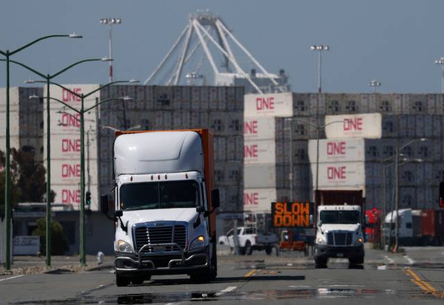 28일(현지 시간) 미국 캘리포니아주 오클랜드항에서 수송트럭들이 적치된 컨테이너 근처를 달리고 있다. AFP연합뉴스