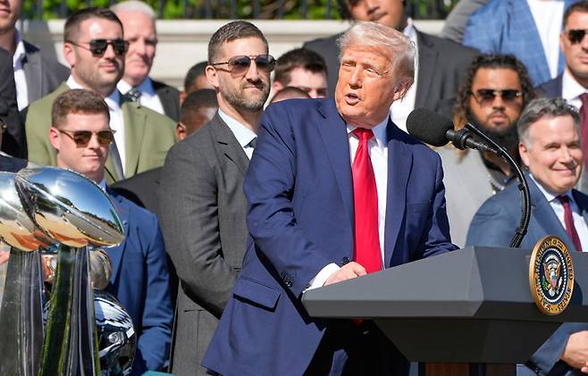 도널드 트럼프 미국 대통령(앞줄 연단에 선 사람)이 28일(현지 시간) 워싱턴 백악관에서 미국프로미식축구리그(NFL) 우승팀 ‘필라델피아 이글스’ 선수단을 환영하는 연설을 하고 있다. 트럼프 대통령은 재집권 100일을 맞는 29일 완성차와 자동차 부품에 부과했던 관세를 완화하는 정책을 내놓기로 했다. 워싱턴=AP 뉴시스