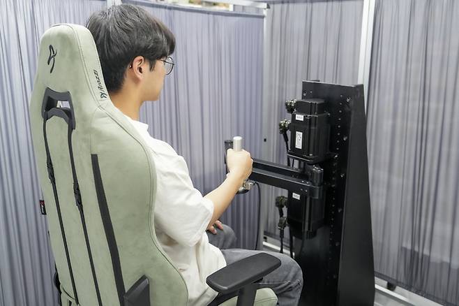 로봇을 이용한 상지 경직 진단 모습. 로봇 팔을 움직이면 사람 팔이 이에 반응하고 이 반응을 신호로 측정해 경직도를 진단한다.