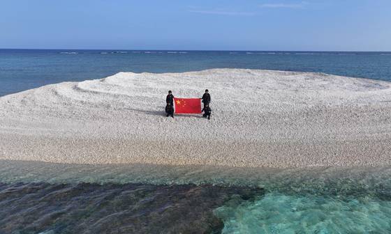 The Chinese coast guard lands on the disputed Tiexian Reef — known as Sandy Cay in the Philippines — in the South China Sea and raises the Chinese flag to assert sovereignty and jurisdiction, according to a report by China’s state-run Global Times on April 24. [SCREEN CAPTURE]