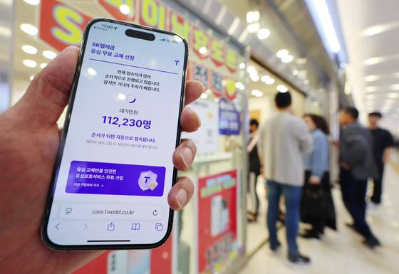 A notice about USIM replacement reservations is posted at an SK Telecom retail store in Seoul on April 28 as the company begins offering a free USIM replacement service following the hacking incident involving customer information. [YONHAP]
