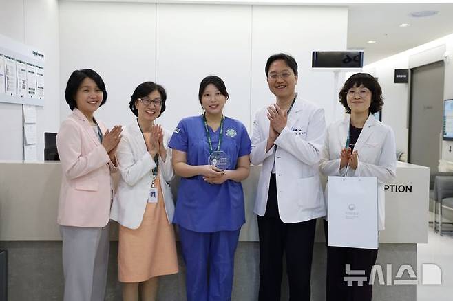 [서울=뉴시스]임신 7개월인 대학병원 소속 간호사가 최근 충북 괴산군 국립괴산호국원에서 경련을 일으키며 쓰러진 40대 환자에게 응급처치를 시행해 생명을 살린 사실이 알려지면서 감동을 주고 있다. 왼쪽에서 세 번째가 최애리 간호사. (사진= 이대목동병원 제공)  2025.04.30. photo@newsis.com.