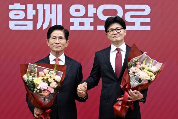 국민의힘 대선 최종 경선에 진출한 김문수(왼쪽)·한동훈 후보가 지난 29일 서울 여의도 당사에서 3차 경선 진출자 발표 뒤 꽃다발을 들고서 기념사진을 찍고 있다. 공동취재사진